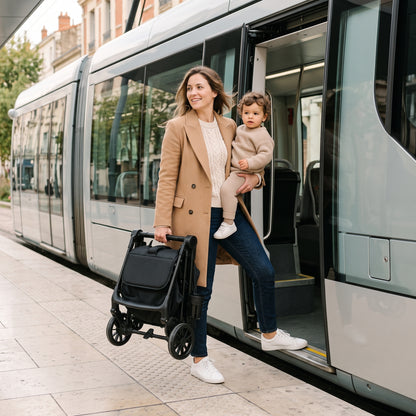 Maman montant dans le tram avec son enfant dans les bras et la Flocon pliée à la main